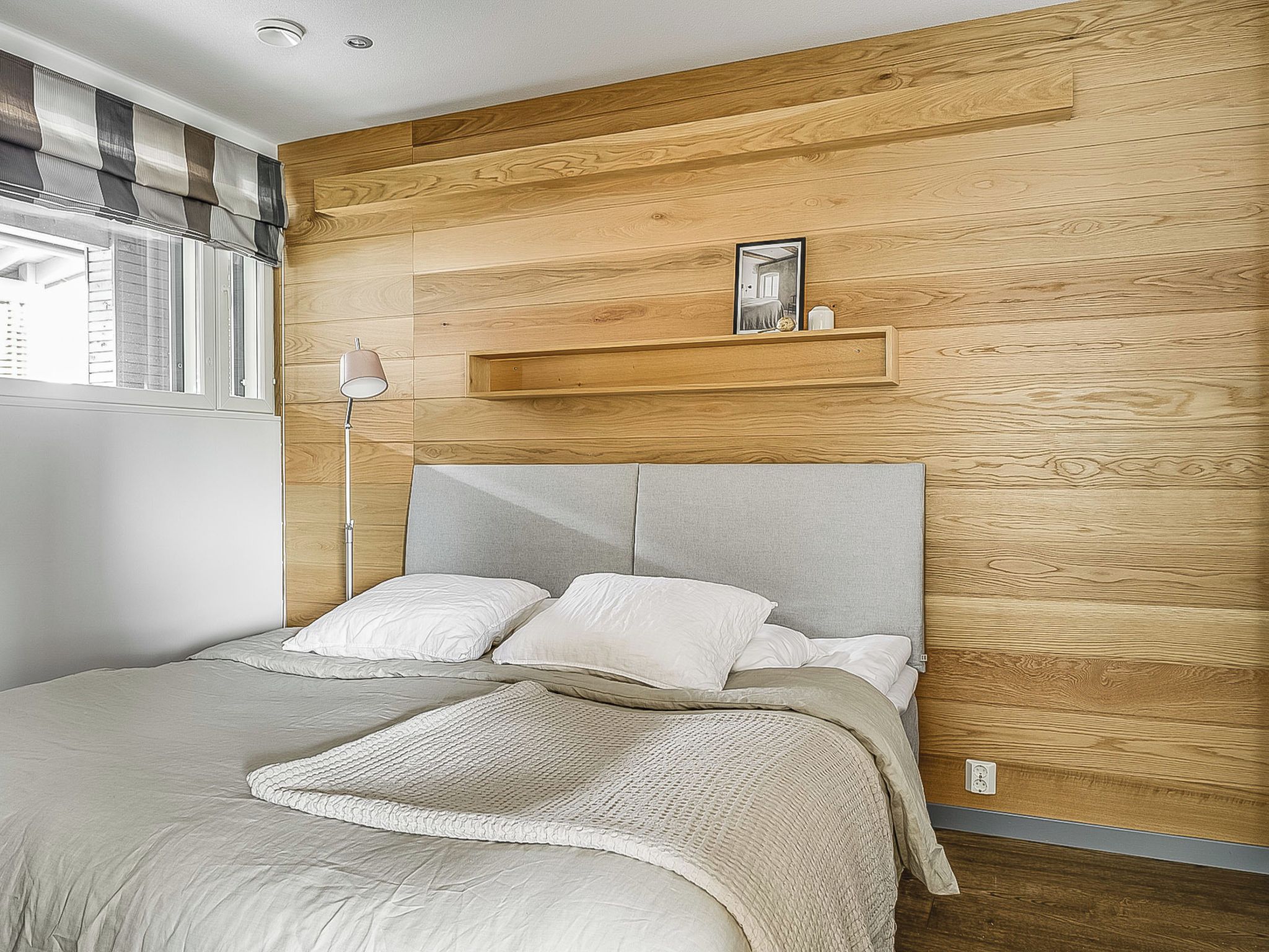 A bedroom with a bed, a bedside lamp, and a wooden headboard.