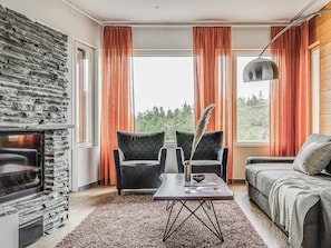 Una sala de estar moderna con una pared de piedra, dos sillones, un sofá, una mesa de centro y una chimenea.