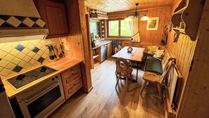 Una cocina acogedora de estilo rústico con armarios de madera, salpicadero de azulejos y un comedor con mesa y sillas.