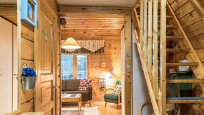 L’intérieur d’un chalet accueillant, avec un escalier en bois, un canapé, une table à manger et une bibliothèque.