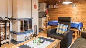Une pièce chaleureuse avec une cheminée, des murs en bois, une table à manger avec des chaises et un fauteuil confortable.