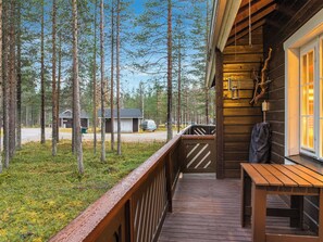 A wooden deck with a table and chairs, surrounded by tall trees. - Nurmennunnu by Interhome (Kittilä)