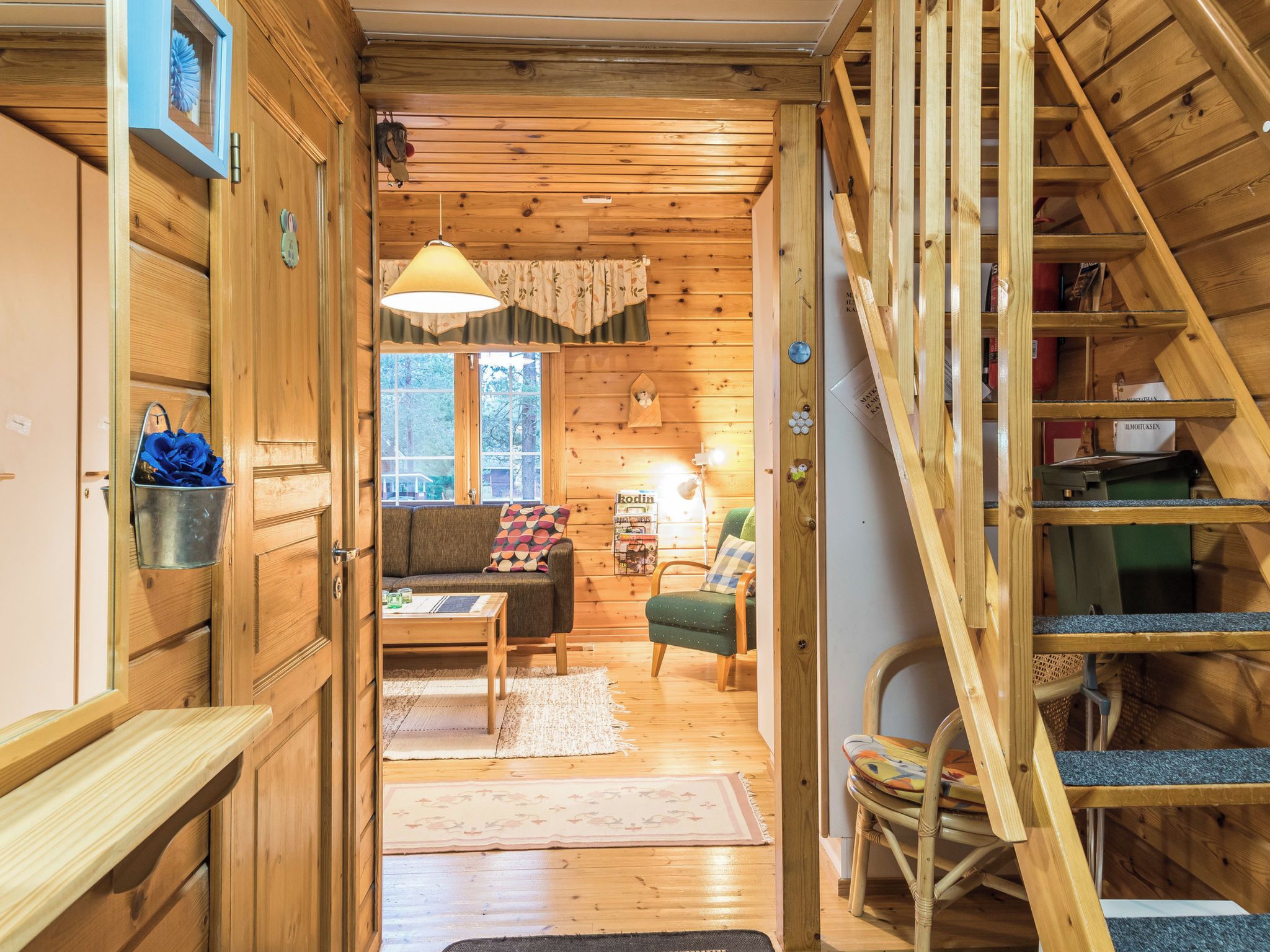 A wooden interior with a staircase, a sofa, a table, and a chair.