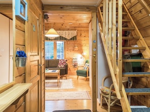 Un interior de madera con una escalera, un sofá, una mesa y una silla.