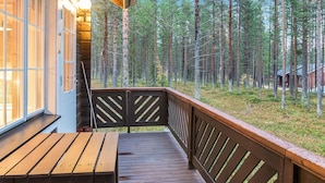 Une terrasse en bois avec une table et des chaises, donnant sur une zone boisée.