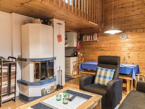 Ein gemütliches Blockhauss-Interieur mit Kamin, Holzwänden, einem Essbereich und einer Sitzecke.