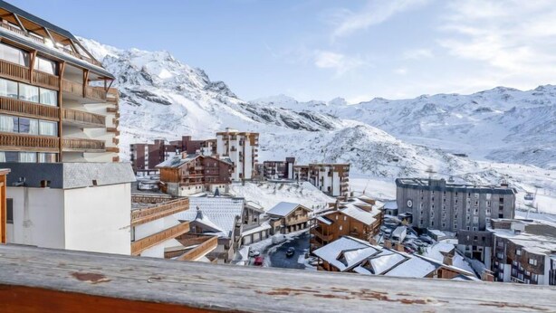 Un paese montano imbiancato dalla neve, con edifici in legno e una seggiovia sullo sfondo.