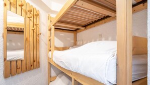 Una stanza con un letto a castello, una testiera in legno e uno specchio.