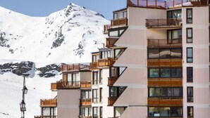 Un hotel a più piani con balconi, sullo sfondo una montagna e cielo sereno.