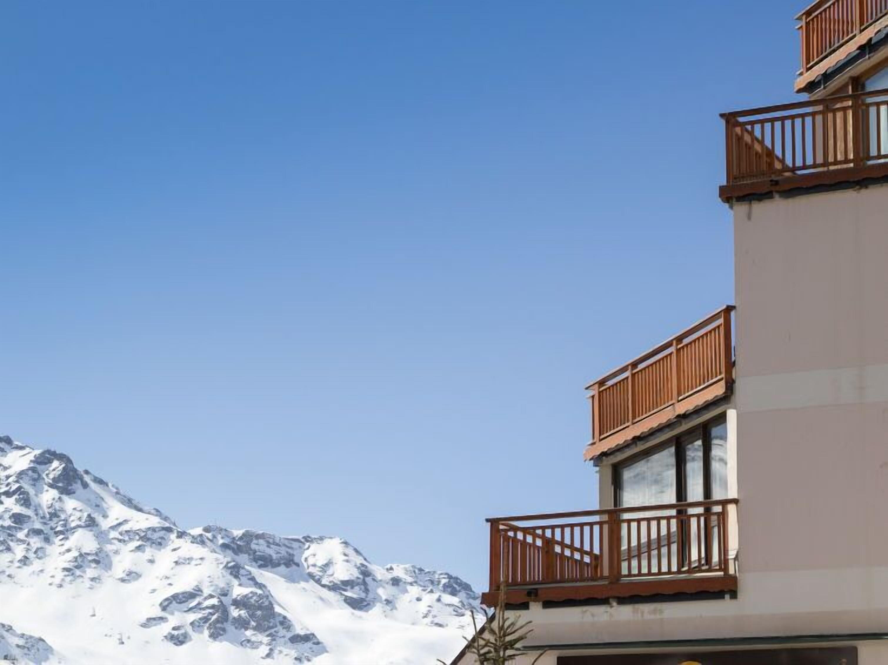 Ein Hotel mit Bergblick, das Balkone mit Holzwerteln und ein modernes architektonisches Design bietet.