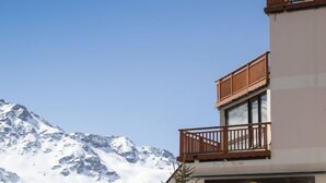 Un hotel con vista sulle montagne, caratterizzato da balconi con ringhiere in legno e un design architettonico moderno.
