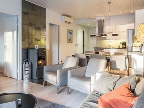 A modern living room with grey sofas, a fireplace, and a kitchen in the background.