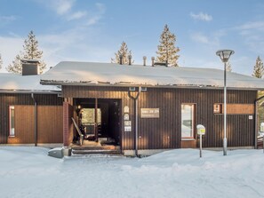A wooden building with a covered entrance, numbered signs, and a snow-covered ground.