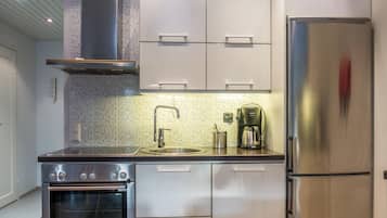 A modern kitchen with stainless steel appliances, including a refrigerator, oven, and coffee maker.