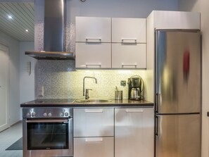 Una cocina moderna con electrodomésticos de acero inoxidable, incluyendo un refrigerador, horno y cafetera.