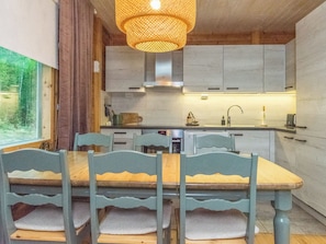 Une cuisine moderne avec des meubles de couleur grise, une table à manger en bois avec des chaises et un luminaire suspendu.