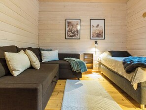 Une pièce confortable avec un canapé, un lit, une petite table et deux tableaux encadrés au mur.