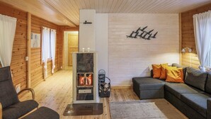 Una sala de estar acogedora con chimenea, paredes de madera, un sofá y un sillón.
