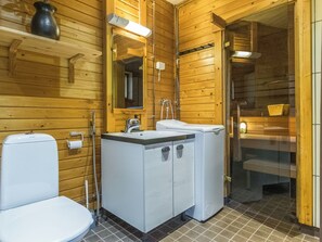 A wooden cabin bathroom with a toilet, sink, and shower area. - Kaakonnokka by Interhome (Ikaalinen)