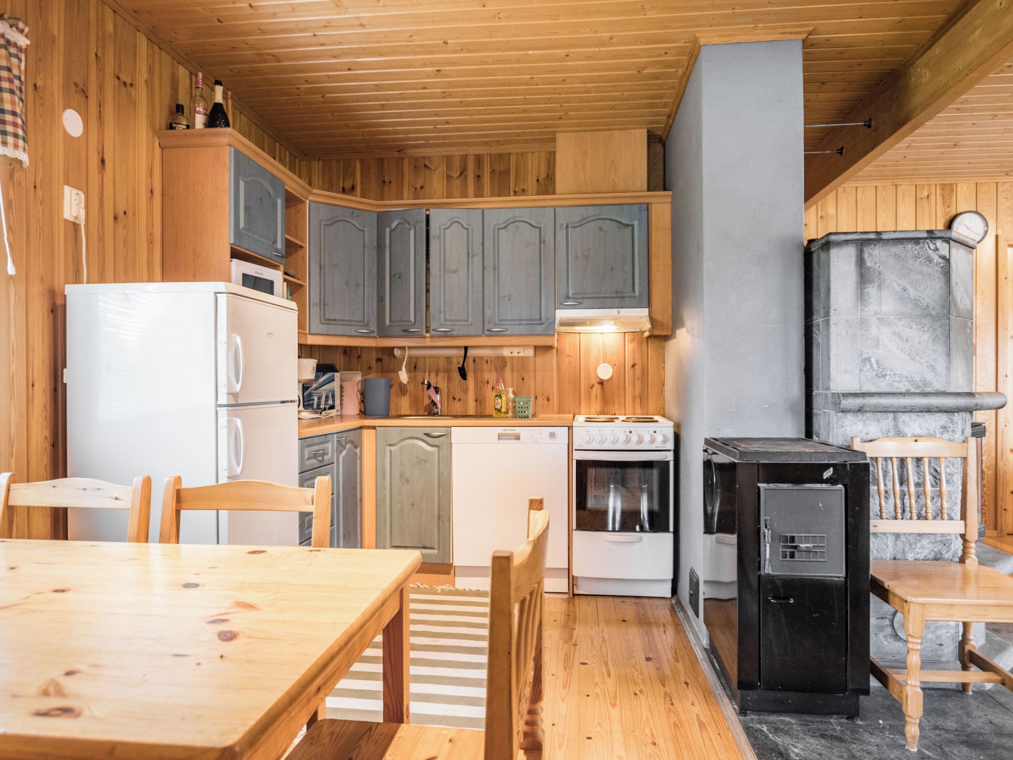 Una cucina compatta con mobili in legno, un fornello, una lavastoviglie e un frigorifero.