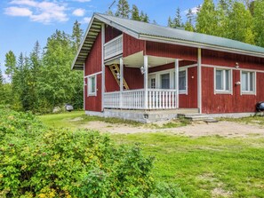 Une maison en bois rouge avec un balcon, une véranda et un garage.