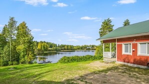 Un chalet au bord du lac, doté d’un toit végétalisé, entouré d’une pelouse et de nombreux arbres.