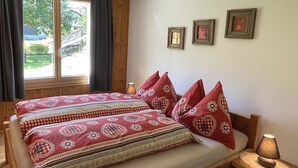 A bed with patterned bedding, a bedside table with a lamp, and three framed pictures on the wall. - Sweda EG Süd by Interhome (Fiesch)