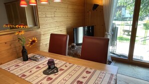A wooden dining table with a patterned tablecloth, a vase with flowers, and a welcome mat. - Sweda EG Süd by Interhome (Fiesch)