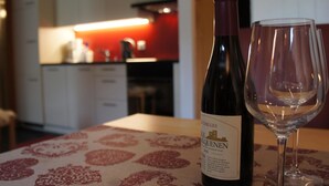 A bottle of wine and an empty glass on a table with a patterned tablecloth. - Sweda EG Süd by Interhome (Fiesch)