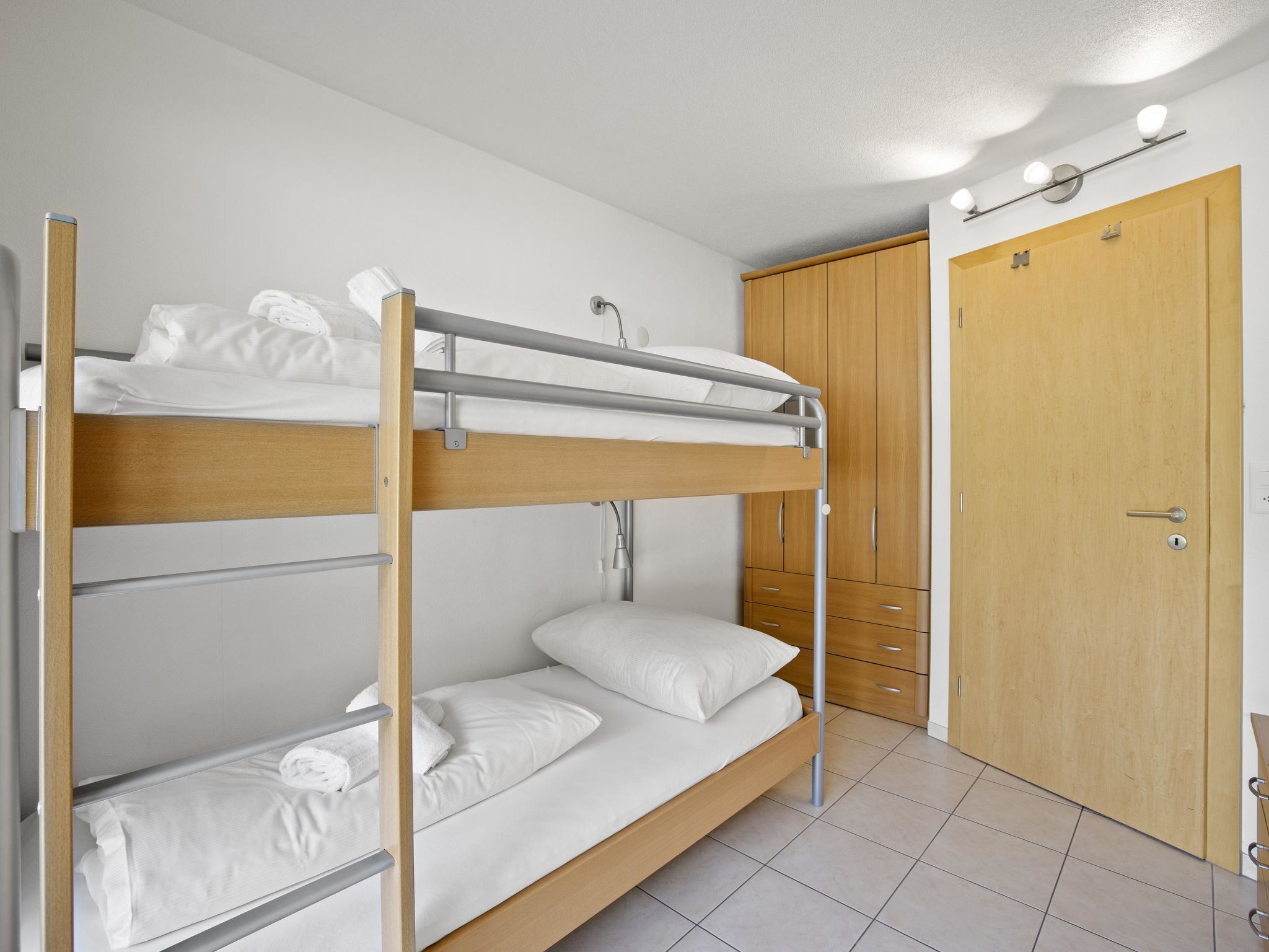 Een slaapkamer met een stapelbed, een garderobe en een deur.