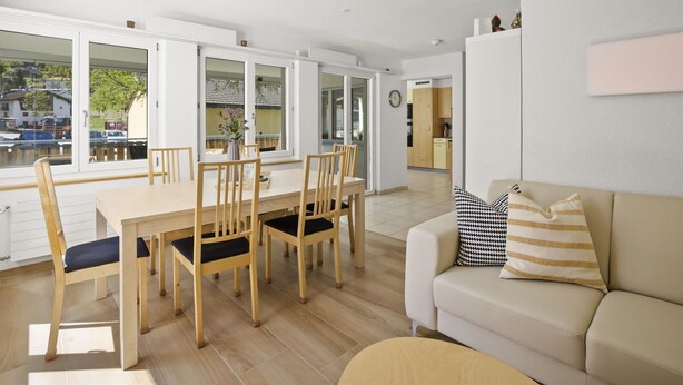 A modern living room with a dining area, a sofa, and a kitchen in the background. - Apartment Ruggli by Interhome (Churwalden)