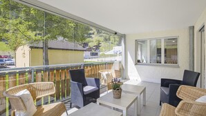 A balcony with wicker furniture, a table with a plant, and a view of a residential area. - Apartment Ruggli by Interhome (Churwalden)