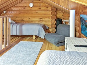 A cozy cabin interior with a bed, a chair, a table, and a painting on the wall.