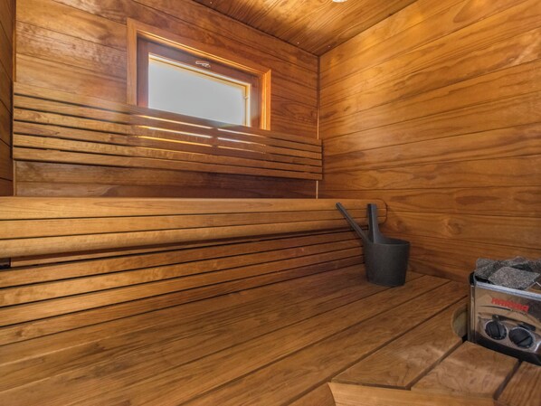 A sauna room with wooden walls and a bench.