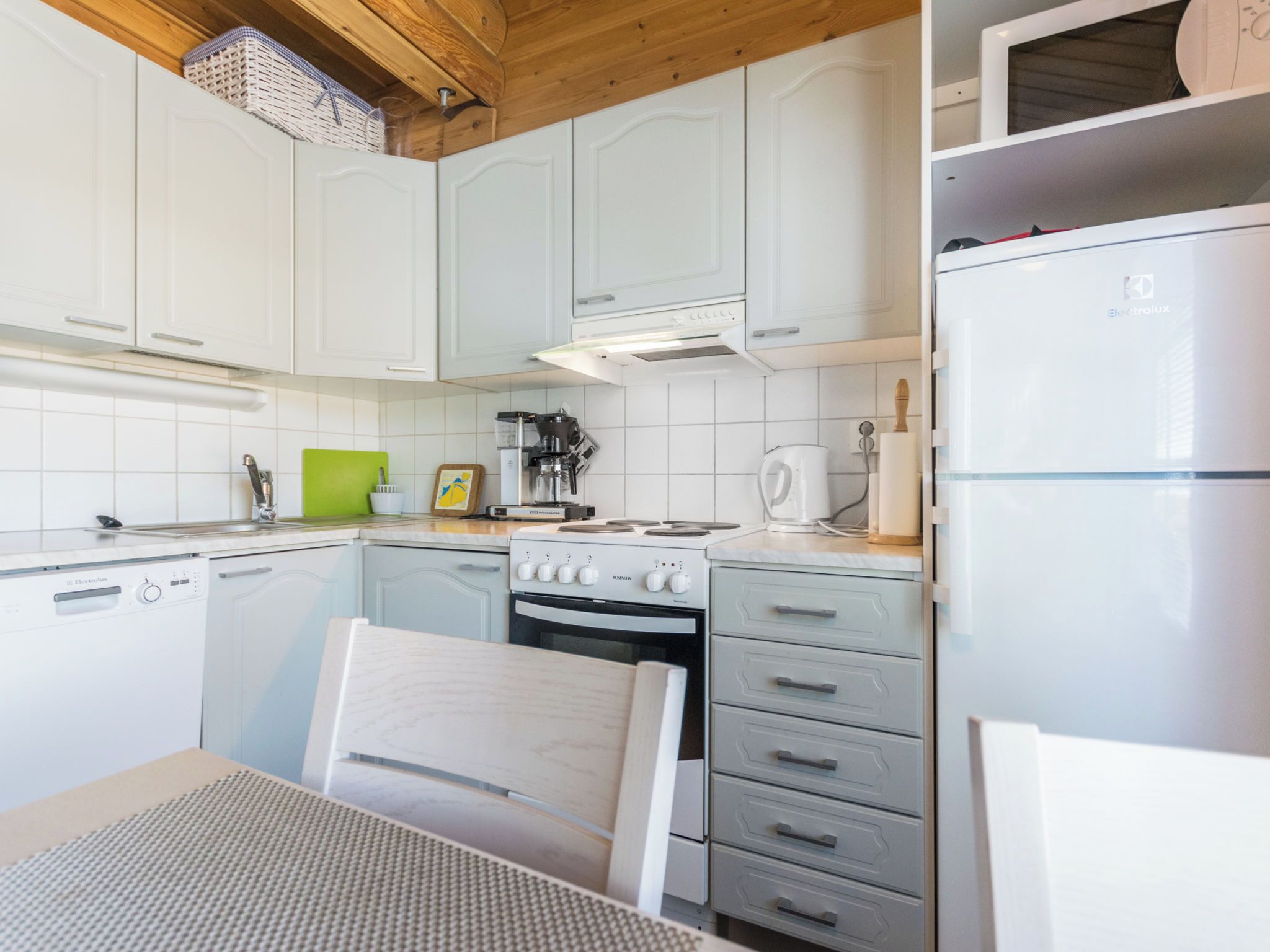 Una cocina compacta con armarios blancos, horno integrado y refrigerador.