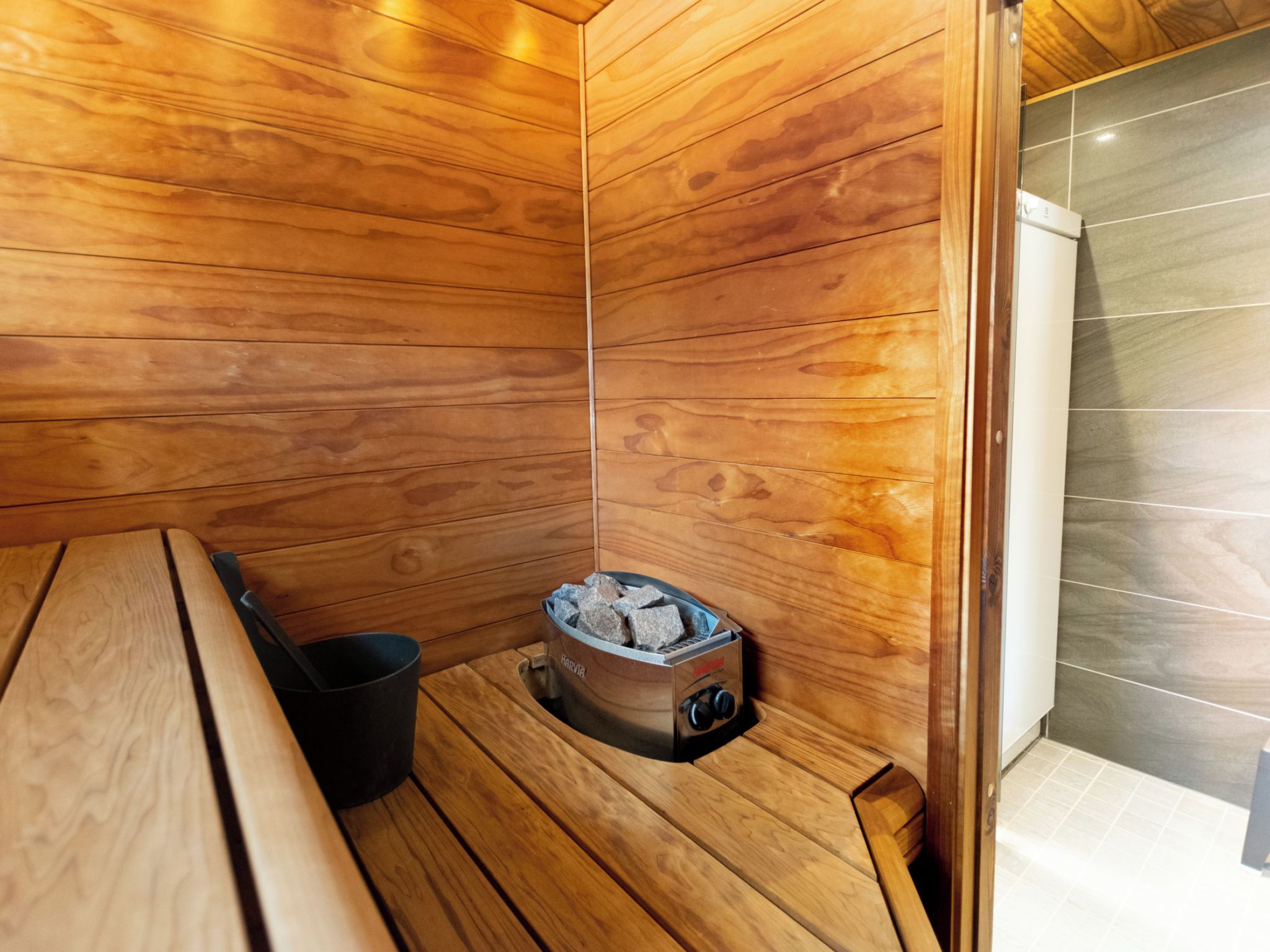 A sauna with wooden walls, a bench, and a stone heater.