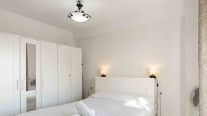 Ein Schlafzimmer mit einem Bett, einem weißen Wandschrank und zwei Wandleuchten.