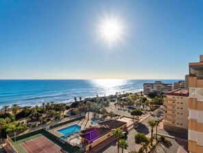 A coastal view with a tennis court, pool, and buildings. - Miramar IV by Interhome (Torrevieja)