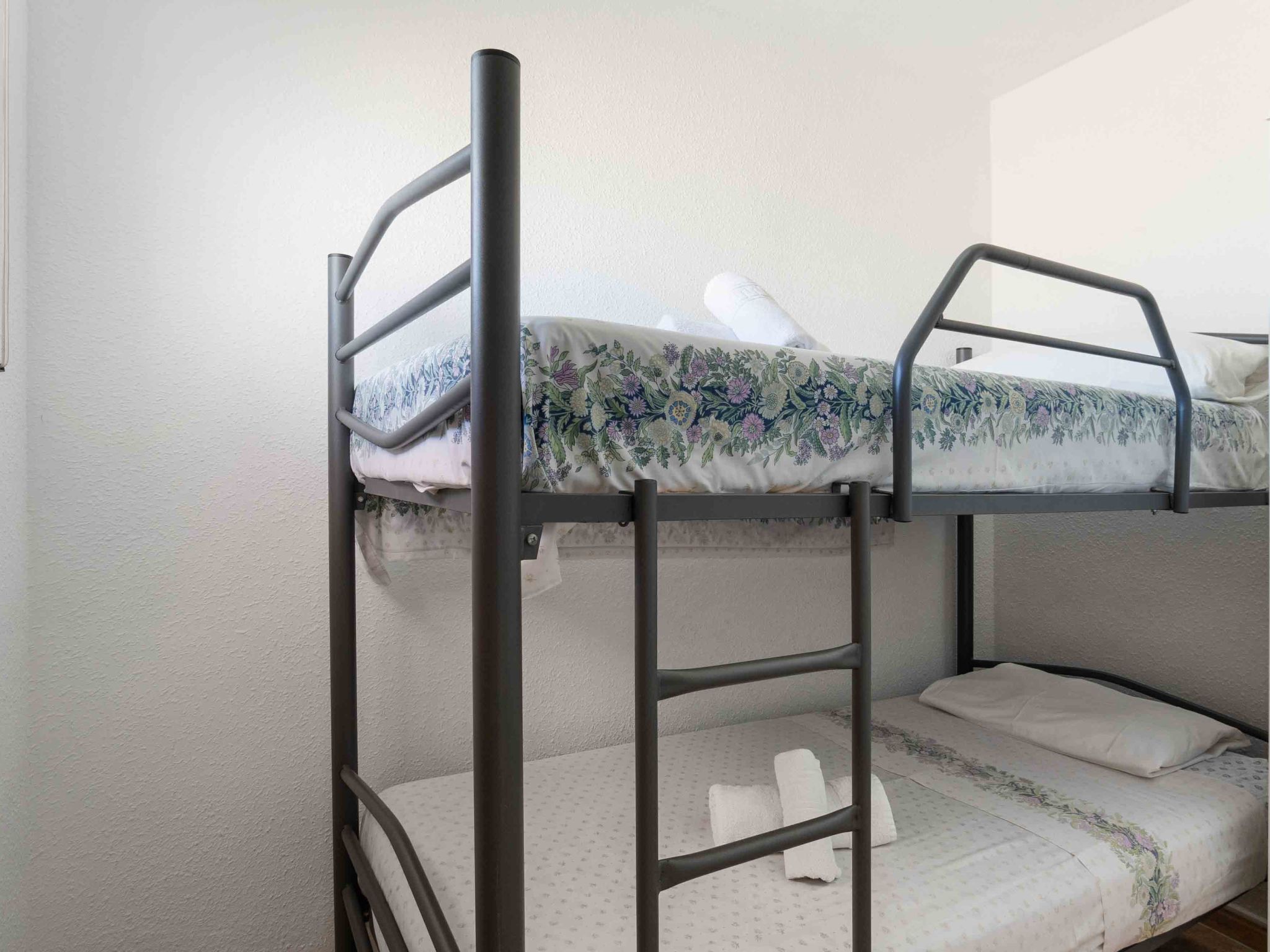 A bunk bed with a floral-patterned mattress and a plain white pillow.