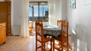 Ein Zimmer mit Esstisch und Stühlen, einem Heizkörper, einem Holzschrank und Blick durch ein großes Fenster.