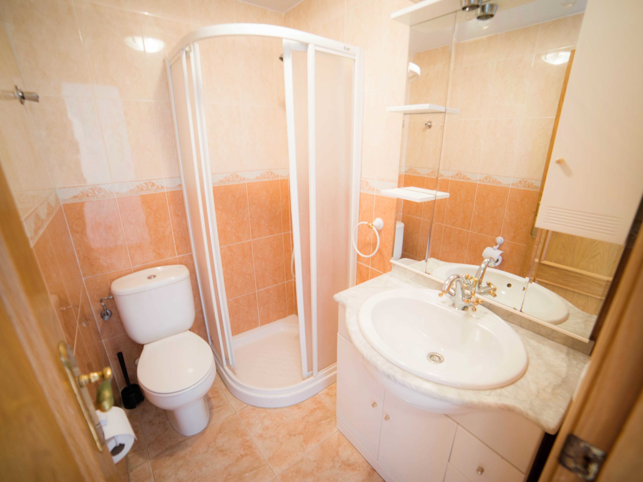 A bathroom with a shower, toilet, sink, and mirror.