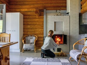 Une pièce chaleureuse avec une cheminée, des murs en bois et des meubles en osier.
