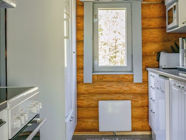 A compact kitchen with a window, wooden wall paneling, a microwave, and a dishwasher.