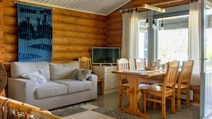 A cozy cabin interior with a sofa, dining table, chairs, and a TV. - Vacation home Norppa by Interhome (Puumala)