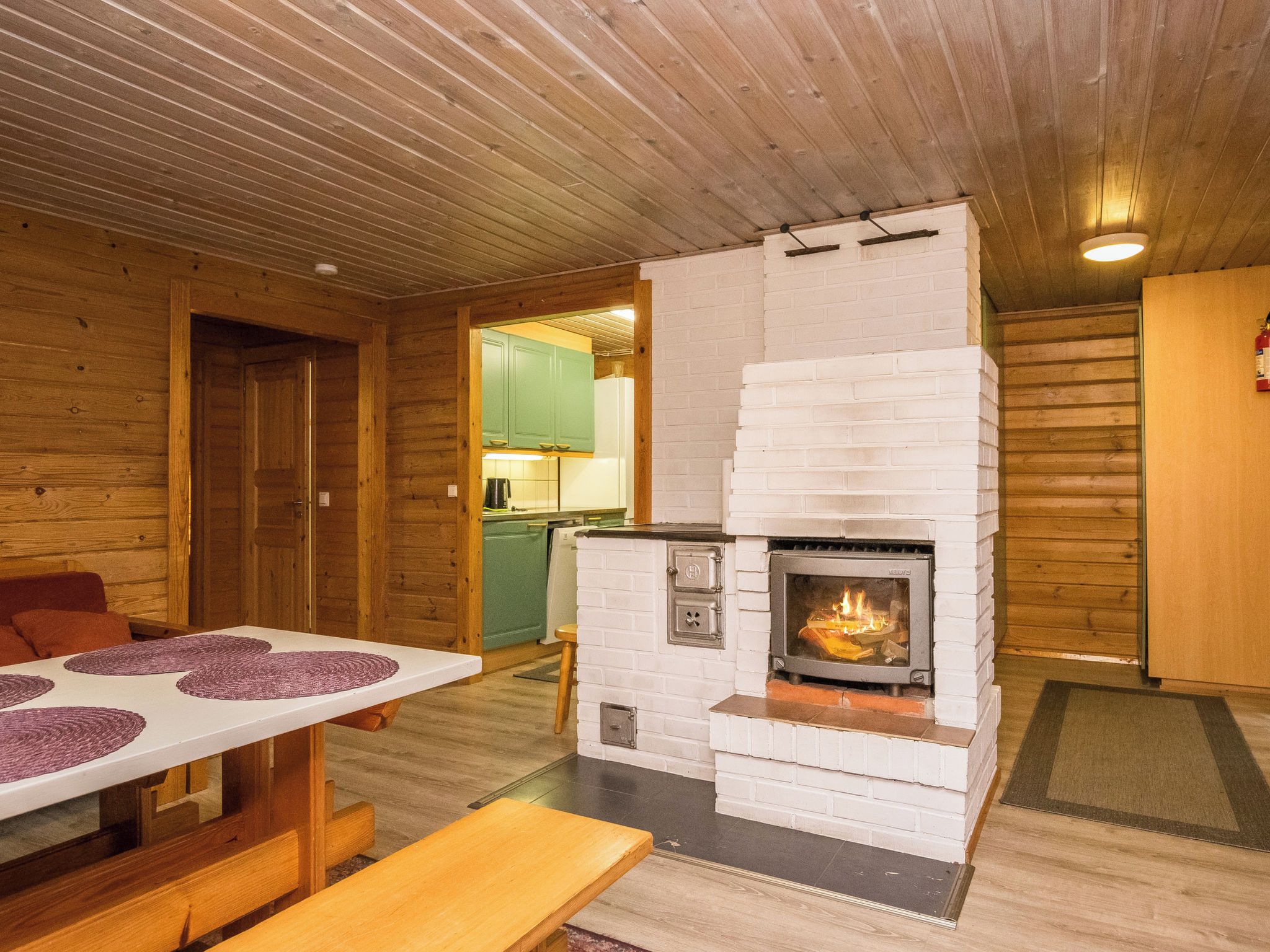 A cozy room with a fireplace, wooden walls, and a dining table with placemats.