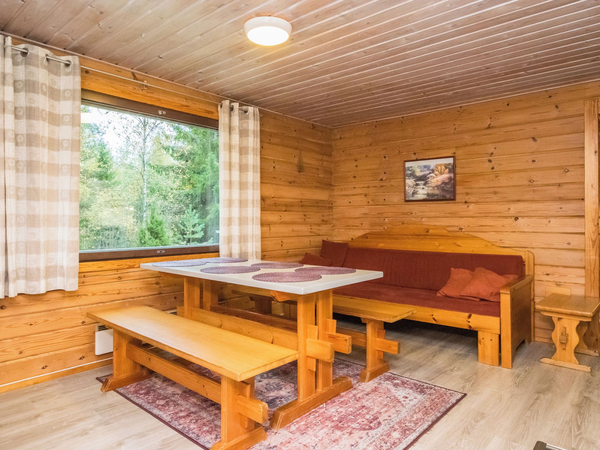 A cabin interior with a wooden table, bench, and sofa.