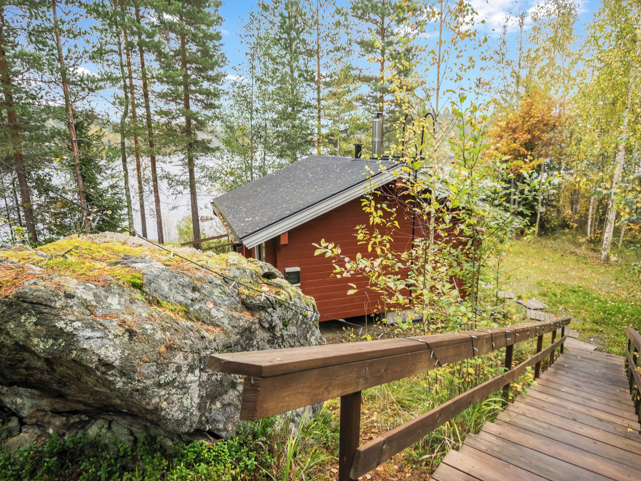A cabin with a wooden deck and a rocky foreground.