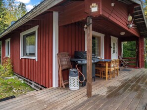 A red wooden cabin with a covered porch, a grill, and outdoor seating. - Iltaniemi by Interhome (Enonkoski)