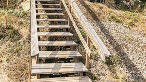 Una escalera de madera que asciende por una ladera rocosa, rodeada de árboles.