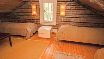 A cozy attic bedroom with two beds, a window, and a small table.